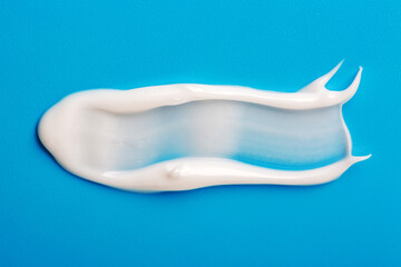 Cosmetic white cream smear on blue background. Beauty skincare creamy product. White lotion texture