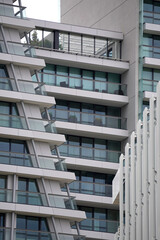 Modern apartment building with glass balconies and geometric facade. Layered design emphasizes...