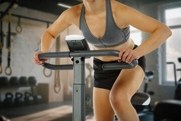 Young woman working out on a stationary exercise bike in a modern gym. 