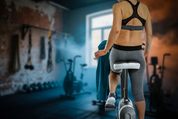 Young woman working out on a stationary exercise bike in a modern gym. 