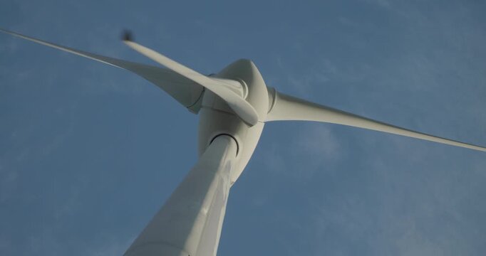 Wind turbine windmill turning in a blue sky with clouds