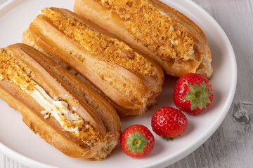 Delicious cream-filled pastries on a plate with fresh strawberries