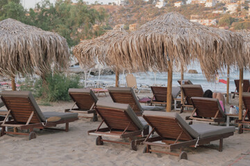 Beach with sun loungers and straw umbrellas. Concept of seaside resort or beach vacation