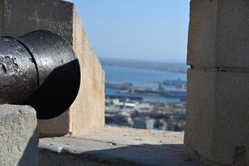 Naklejka premium antyczna żeliwna armata patrzy na miasto z zamku sw barbary w Alicante