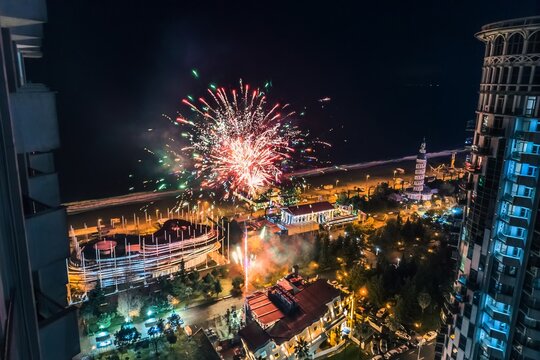 Fireworks explosion over night city and coastline, view from above - Powered by Adobe