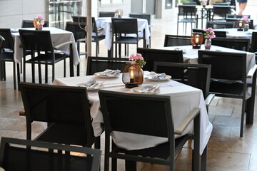 ładnie zastawione puste stoły czekają na gości restauracji świeca na środku białe obrusy