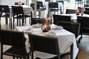ładnie zastawione puste stoły czekają na gości restauracji świeca na środku białe obrusy