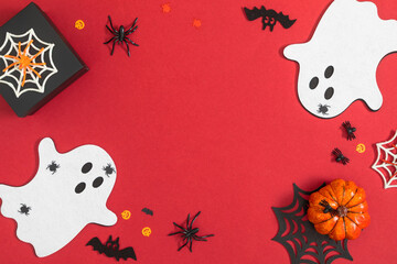 Halloween design with cute flying ghosts, spiders with webs and black bats on a dark red surface...