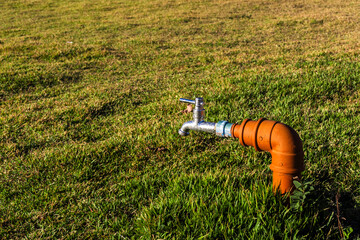 Water valve in the garden with green grass background in sunny day in Brazil
