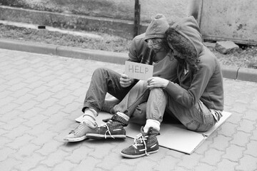 Homeless people with sign Help on carton outdoors, space for text. Black and white effect