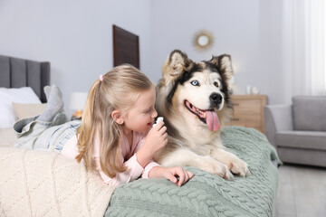 Girl suffering from allergy with her dog on bed at home