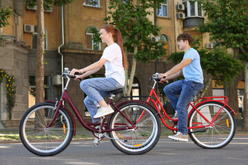 Fototapeta premium Teenage girl and boy riding bicycles on city street