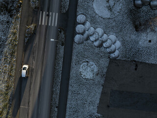 Top-down aerial view of a snowy Tallinn road in the Seaplane Harbour district. A lone electric car...