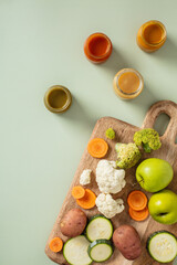 Flat lay of fresh vegetables, fruits, and vibrant sauces on cutting board, including carrots, broccoli, apples, and zucchini.