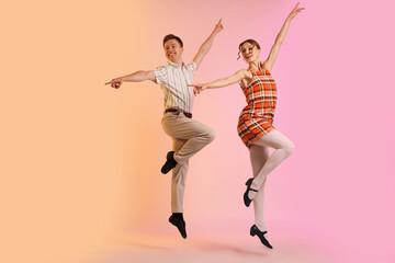Happy couple in retro outfits dancing on color background