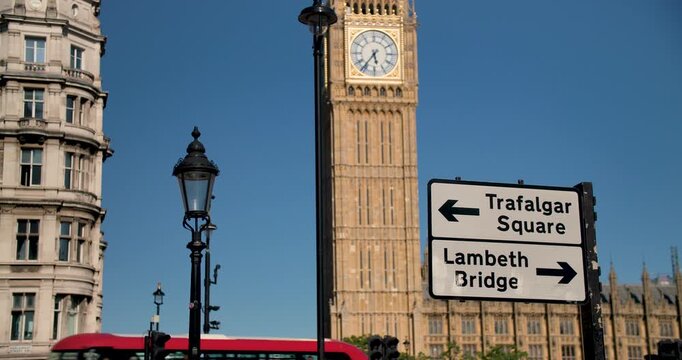 Big Ben, Houses of Parliament and road sign to Trafalgar Square and Lambeth Bridge against a blue sky, summer, London, England