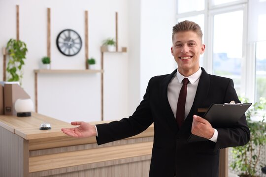 Portrait of smiling receptionist with clipboard in hotel - Powered by Adobe