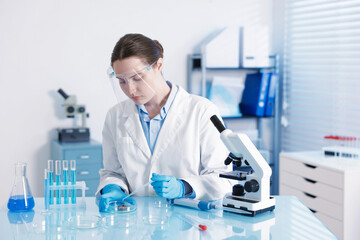 Scientist working with sample in Petri dish at table in laboratory