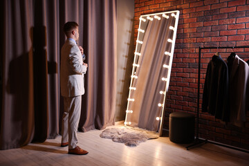 Handsome man getting ready near mirror indoors