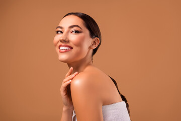 Obraz premium Smiling young woman with flawless skin and elegant hairstyle posing in a stylish spa-themed setting.