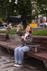Woman with broken umbrella on bench outdoors