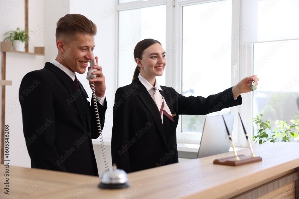 Poster smiling receptionists working at reception desk in hotel