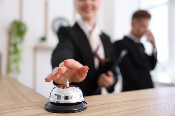 Client pushing service bell at reception desk in hotel, closeup