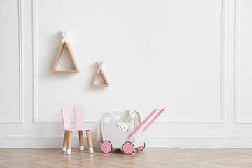 Child's toys, chair and wigwam shaped shelves on white wall indoors. Interior design © New Africa