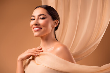 Portrait of a smiling young woman with glowing healthy skin in an elegant beige therapy setting