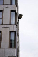 Modern street lamp mounted on a tall metal pole beside a contemporary office building with large...