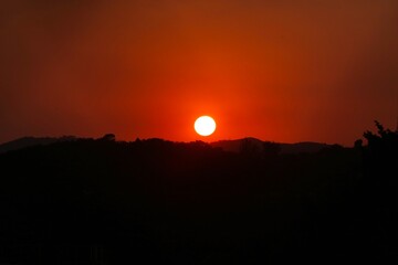 Pôr do sol intenso com céu em tons de vermelho e laranja sobre silhuetas de montanhas. Uma cena dramática e serena, perfeita para representar a beleza natural, a paz e a contemplação.