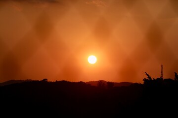 Pôr do sol intenso com céu em tons de vermelho e laranja sobre silhuetas de montanhas. Uma cena dramática e serena, perfeita para representar a beleza natural, a paz e a contemplação.
