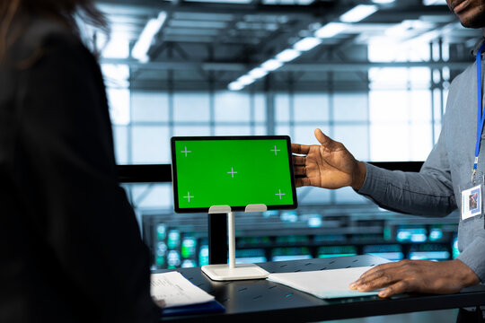 Admins in data center use mockup tablet, inspecting server rackmounts, updating network topologies, close up shot. IT specialists talking, using chroma key device, ensuring stable operations