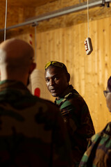 Army general speaking with recruits in shooting range, teaching them about weapons handling at...