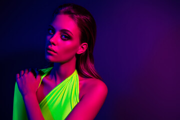 Portrait of a vibrant young woman illuminated by bright neon lights in a modern glamorous setting