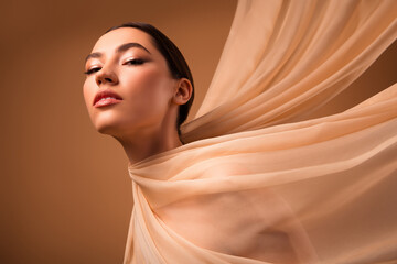 Sensual portrait of a young woman with flowing fabric accentuating her beauty, featuring soft makeup