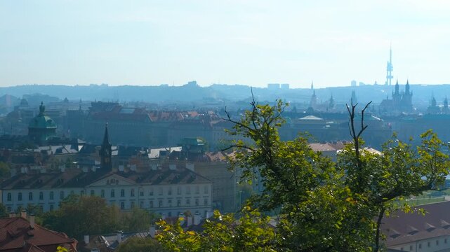 Panning view of prague's cityscape from petrin hill showcases the vltava river, iconic landmarks, and traditional architecture under a clear sky