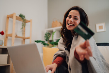 Happy woman shopping online using laptop and credit card at home