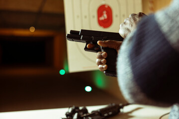 Indoor shooting range client cocking handgun, setting mechanism up for firing. Close up shot of...