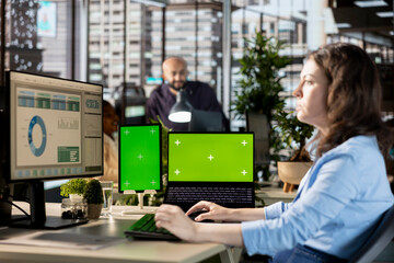 Young manager works with infographics next to isolated display at the desk, working on enterprise...