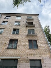 Soviet-era residential brick building with broken windows and balconies, low angle view