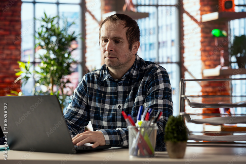 Poster employee at desk completing spreadsheets on laptop, entering numerical data into cells, calculating 