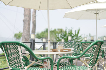 In Incheon, a fashionable beachside cafe terrace with elegant parasols, cozy chairs, and scenic...