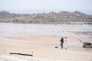 In June 2025, a Korean man and woman in their late fifties walk along the peaceful seashore,...