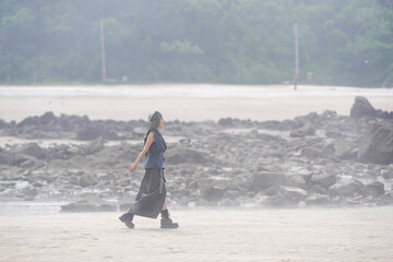 In June 2025, a Korean man and woman in their late fifties walk along the peaceful seashore,...