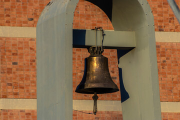 ntique bronze bell hanging in a metal frame against a red brick wall in Brazil. Symbol of tradition...