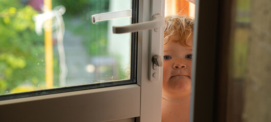 Child Standing at an Open Door During a Warm Afternoon in a Backyard Garden