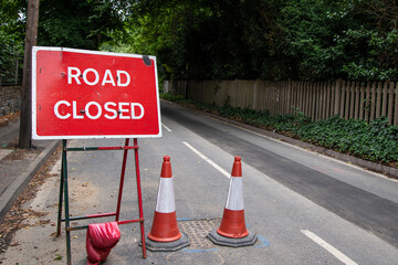 Red "Road Closed" sign positioned by the roadside. UK traffic signage used for roadworks, emergencies, or closures. Clear, bold text in a natural outdoor or urban setting.