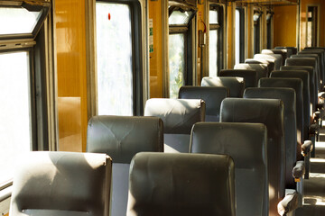 Vintage train carriage interior with rows of old leather seats and wooden wall panels