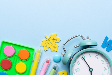 Alarm clock and school supplies on light blue background top view, copy space for your design. Back...